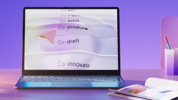 Laptop displaying the words Co-author, Co-assist, Co-produce, Co-draft, and Co-innovate to convey Copilots capabilities on a purple background, with a pen holder and a notebook on the desk
