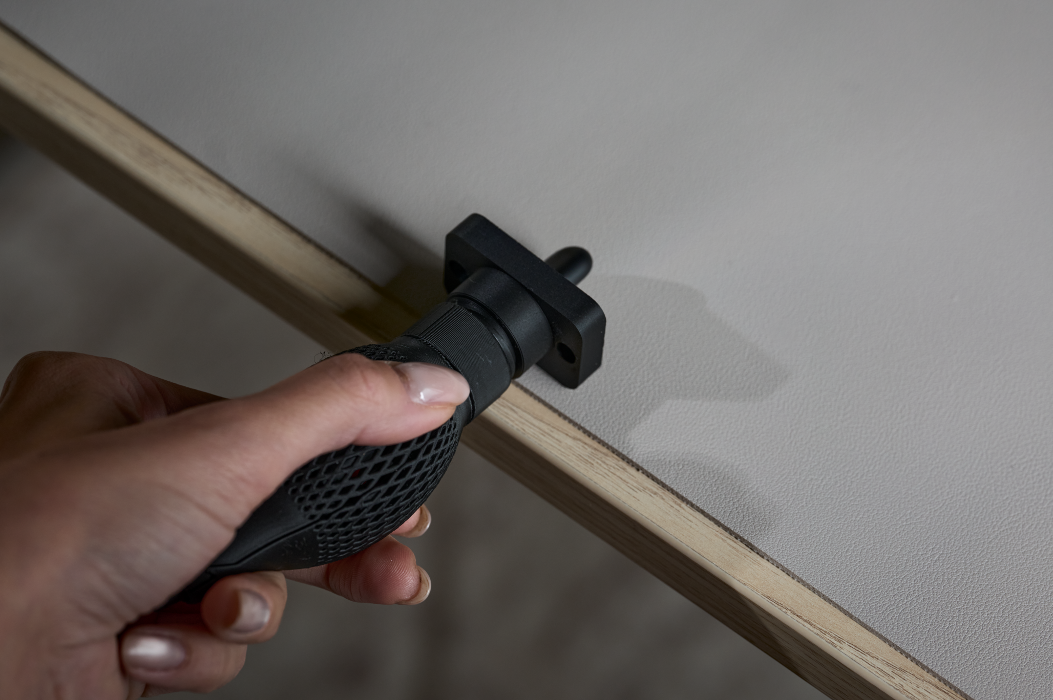 A hand uses the edge of a table to twist the cap with one hand.