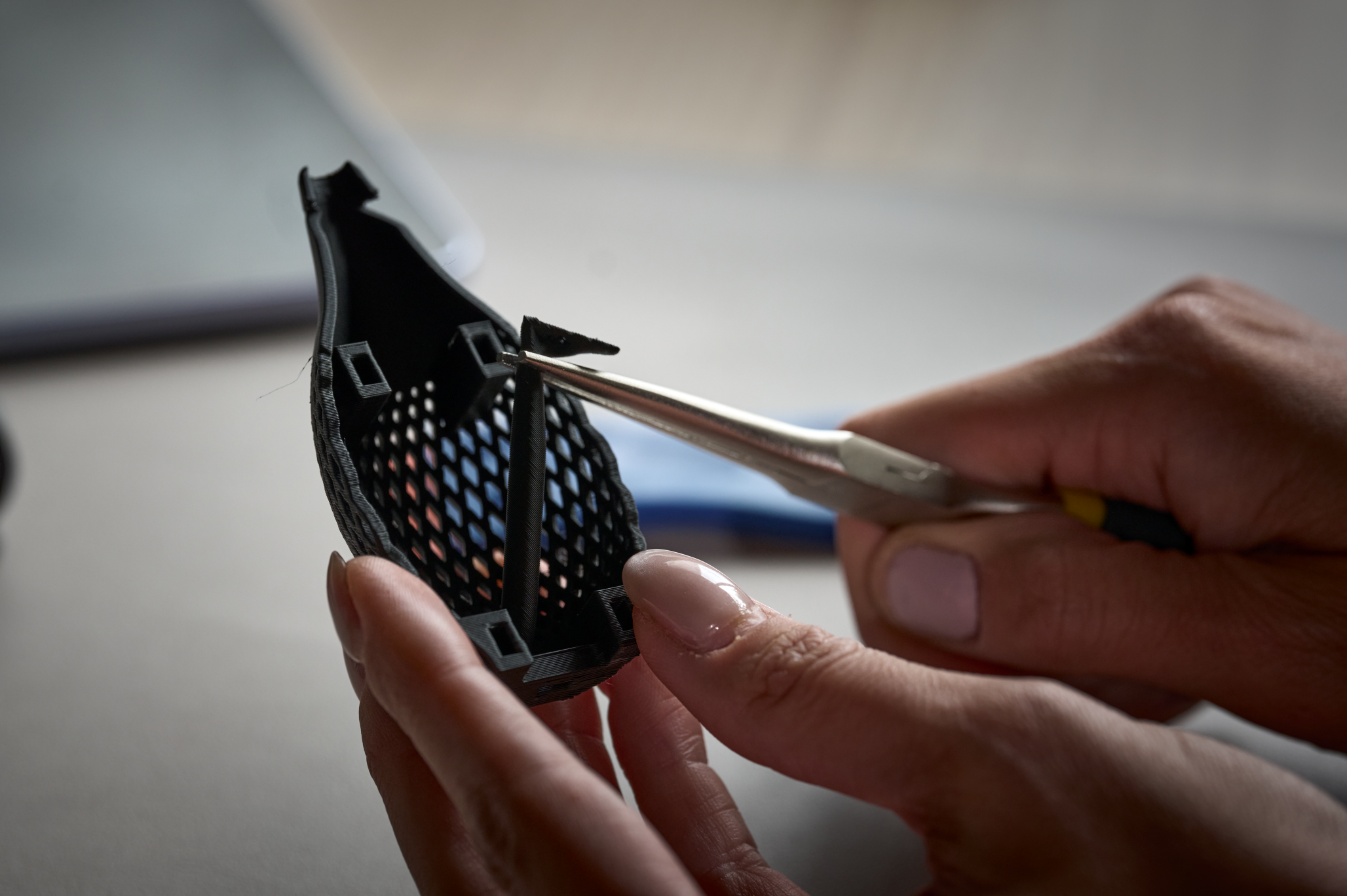 Tweezers are used to remove support material from a printed Surface Slim Pen grip part.