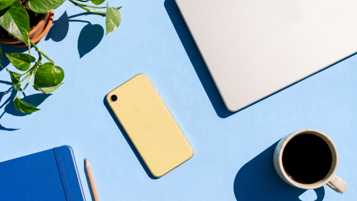 Screenshot that shows a phone, laptop, and coffee cup on a blue desk.
